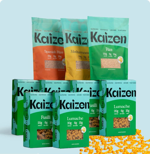The ShredHappens Bundle by Kaizen Food Company is on display, featuring gluten-free pasta boxes in green for Fusilli and Lumache, and rice packs in muted orange and green showcasing Spanish Rice and Mediterranean varieties, accompanied by scattered corn kernels.